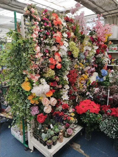 Parete espositiva di fiori artificiali colorati e piante decorative nel vivaio Green Service Oulx